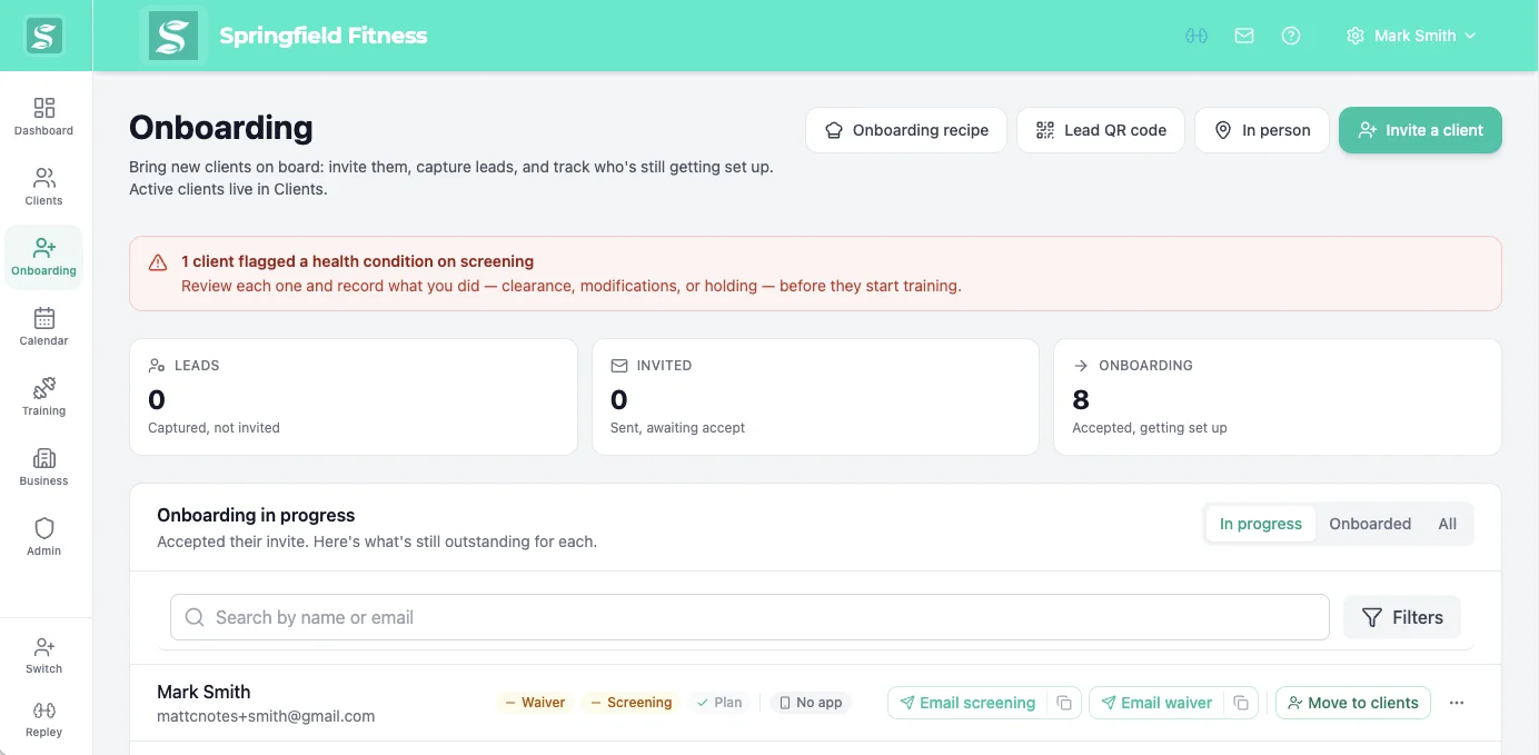 Trainer onboarding hub on a laptop tracking which clients still need a waiver, screening, or plan, with a health-flag review banner across the top