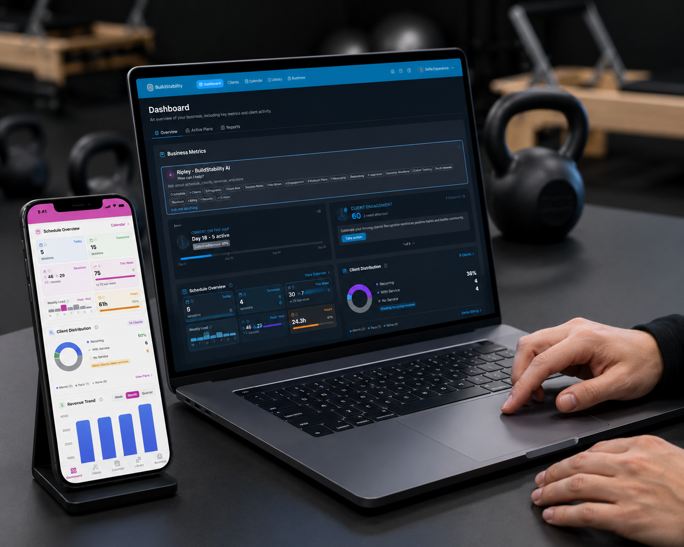 BuildStability dashboard on a MacBook with the trainer app open on iPhone, in a premium gym studio